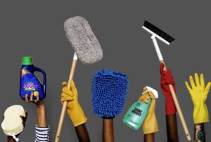 Hands holding cleaning tools and solutions